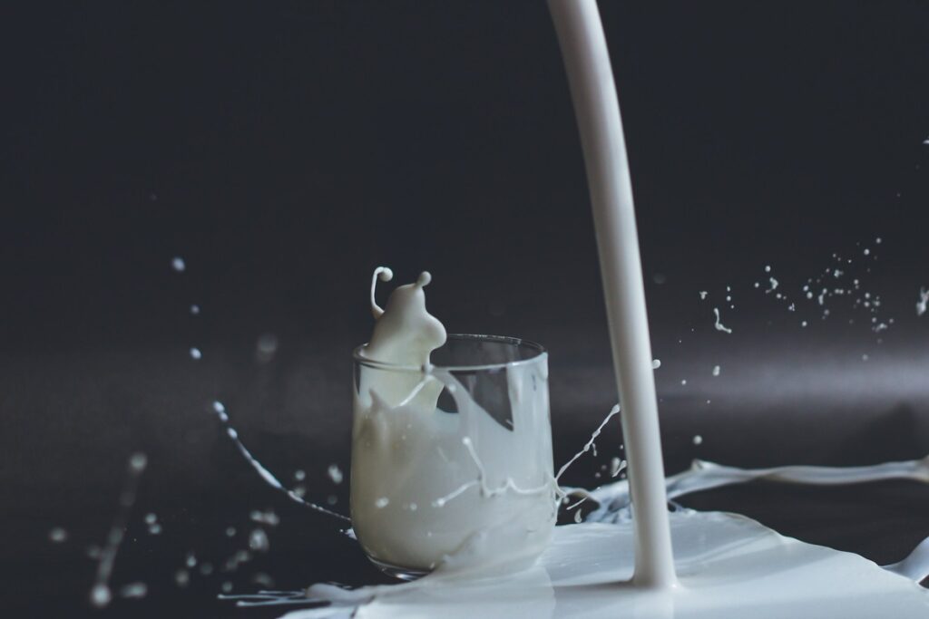 Glass of milk with some spilled on the floor