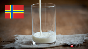 Milk being poured into a glass with the Orkney Islands flag in the background.