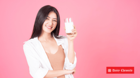 A woman holding a glass of milk with text about major investments in the Asian dairy industry