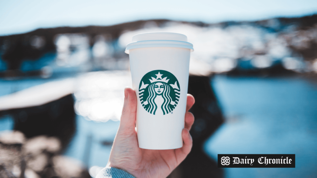 Hand holding a Starbucks coffee cup featuring the new Pecan Crunch Oatmilk Latte